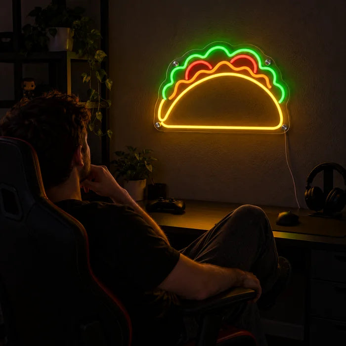 Taco Time Neon LED Sign above a gaming desk, a gamer in a gaming chair in front of it