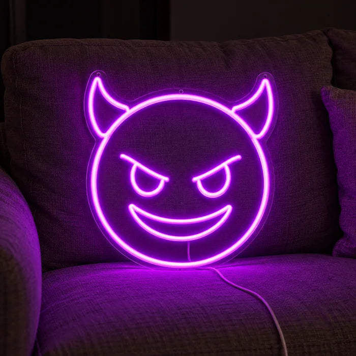 Devil Grin Neon LED Sign on a cosy sofa between cushions and a throw
