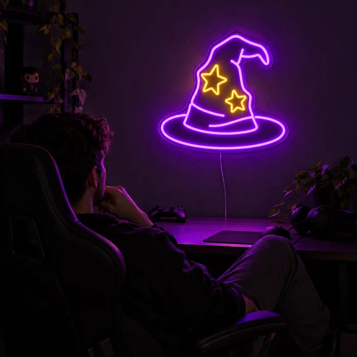 Wizard Hat Neon LED Sign above a gaming desk, a gamer in a gaming chair in front of it