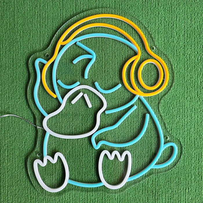 Entenfigur Neon LED Schild ausgeschaltet auf grünem Stoff, hellblaue Linien und goldene Kopfhörer sichtbar