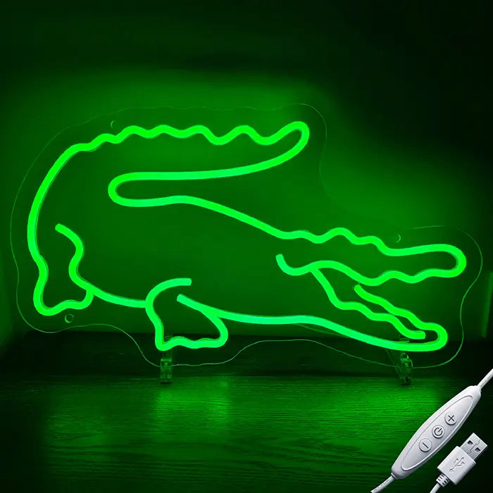 Krokodil Neon LED Schild in Grün, leuchtend auf einer Holzfläche, daneben das USB-Kabel mit Inline-Dimmer