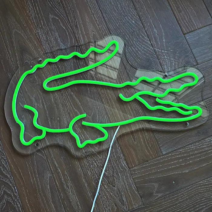 Krokodil Neon LED Schild von oben auf Holzdielen, ausgeschaltet, weißes Anschlusskabel nach unten geführt