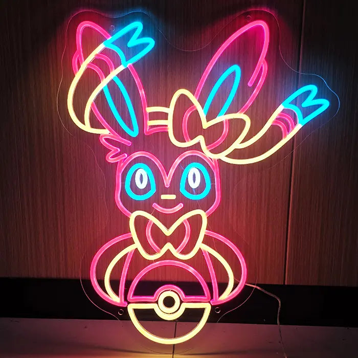 Fantasietier Neon LED Schild leuchtet in Rosa, Gelb und Blau frontal an einer dunklen Holzwand