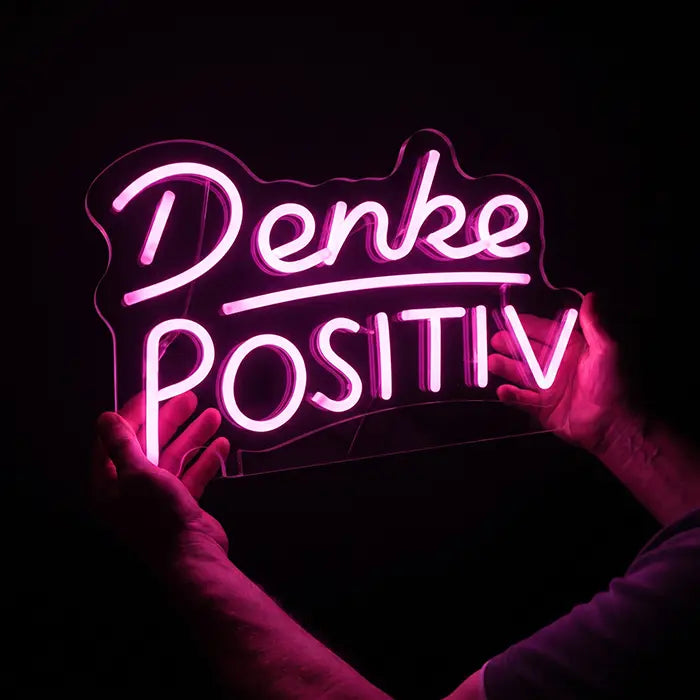 Denke Positiv Neon LED Schild von Händen gehalten, transparente Acrylplatte und rosa Neon-Linien sichtbar