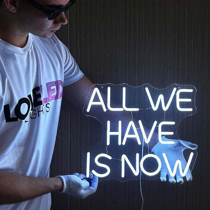 All We Have Is Now Neon LED Schild leuchtet weiß, während der Inline-Dimmer am Kabel bedient wird