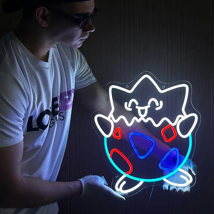 Eierschalen-Figur Neon LED Schild fertig montiert an dunkler Wand, leuchtend in Weiß, Hellblau, Rot und Blau
