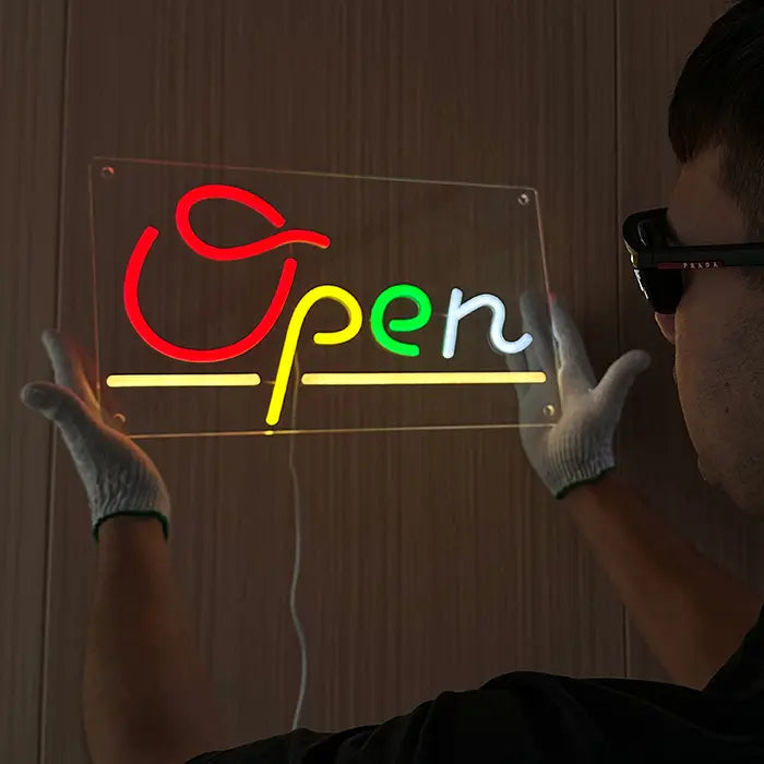 Open Neon LED Schild seitlich gehalten, weißes Anschlusskabel hängt unter der Acrylplatte