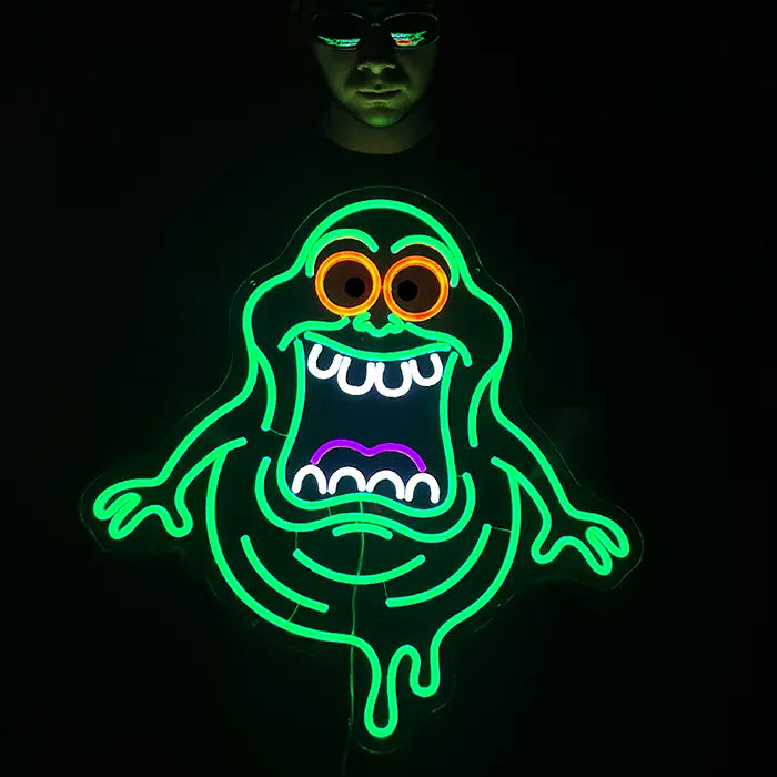 Schleimgeist Neon LED Schild strahlt grün in einem abgedunkelten Raum und wirft weiches Licht auf die Wand dahinter