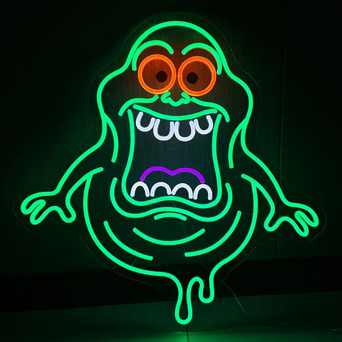 Schleimgeist Neon LED Schild leuchtet grün an dunkler Wand, orange Augenringe und weit offener Mund mit weißen Zähnen