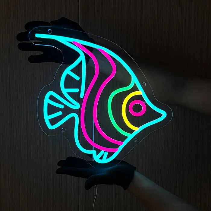 Ocean Fish Neon LED Sign held with gloves, the motif glowing against a dark wooden wall