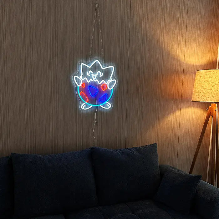 Pokémon Togepi Neon LED Sign on a dark wooden wall above a sofa, a floor lamp beside it