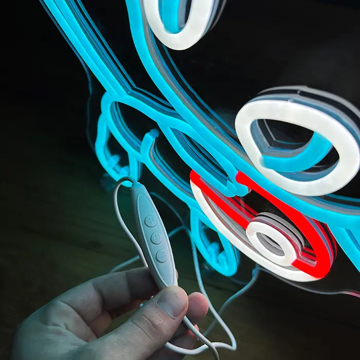 Pokémon Mew Neon LED Sign in blue in close-up, the inline dimmer held in hand in front of the neon lines