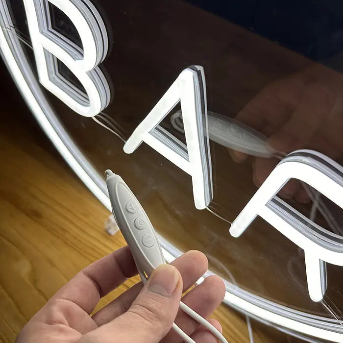 BAR Neon LED Sign close up, the inline dimmer with plus, on/off and minus buttons resting in a hand