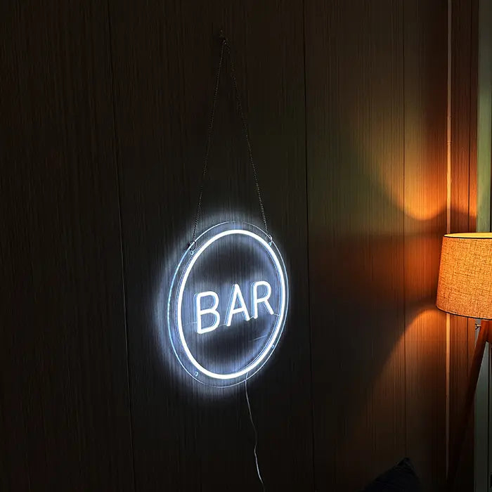 BAR Neon LED Sign on a dark wooden wall, the white glow standing out beside the warm floor lamp