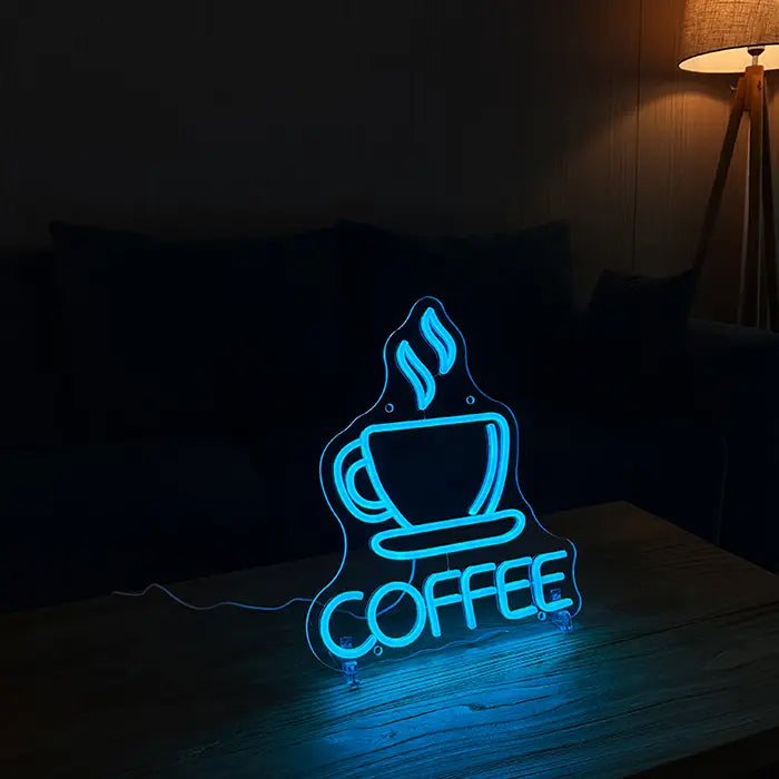 Coffee Cup Neon LED Sign on stands on a wooden table, sofa and floor lamp behind