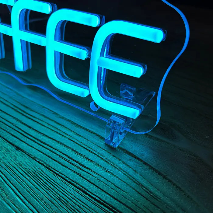 Coffee Cup Neon LED Sign in detail with a stand on a wooden surface, letters glowing