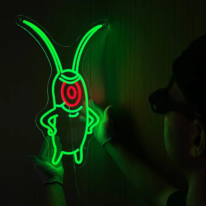 The Plankton Neon LED Sign being lined up on the wall, a person in gloves holds it in place