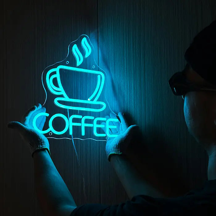 Coffee Cup Neon LED Sign being lined up on the wall, a person in gloves holds it in place