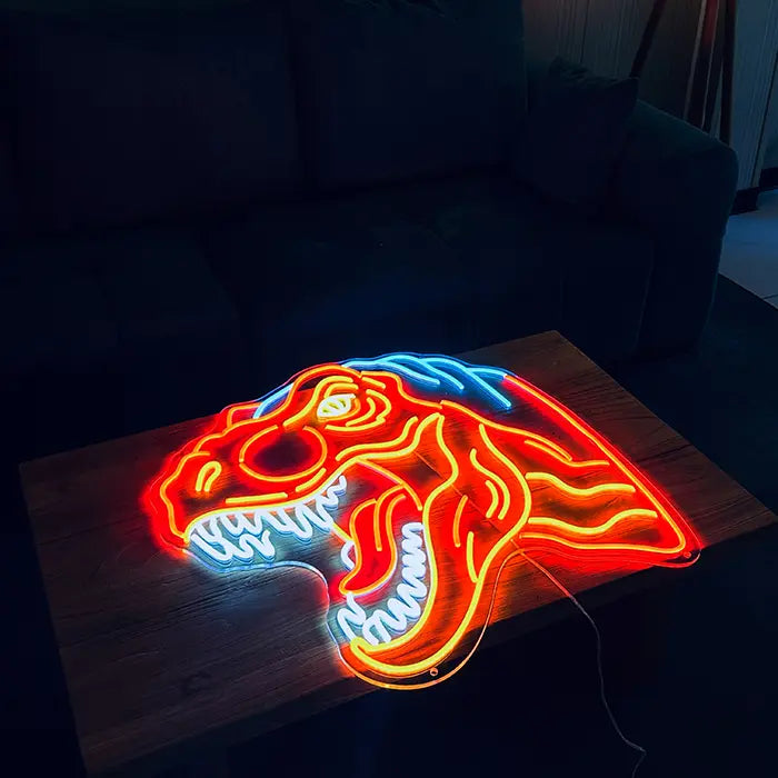 T-Rex Dino Neon LED Sign lying on a wooden table in front of a sofa, glowing red and orange
