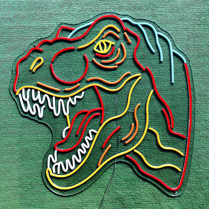 T-Rex Dino Neon LED Sign switched off on a green surface, full outline visible