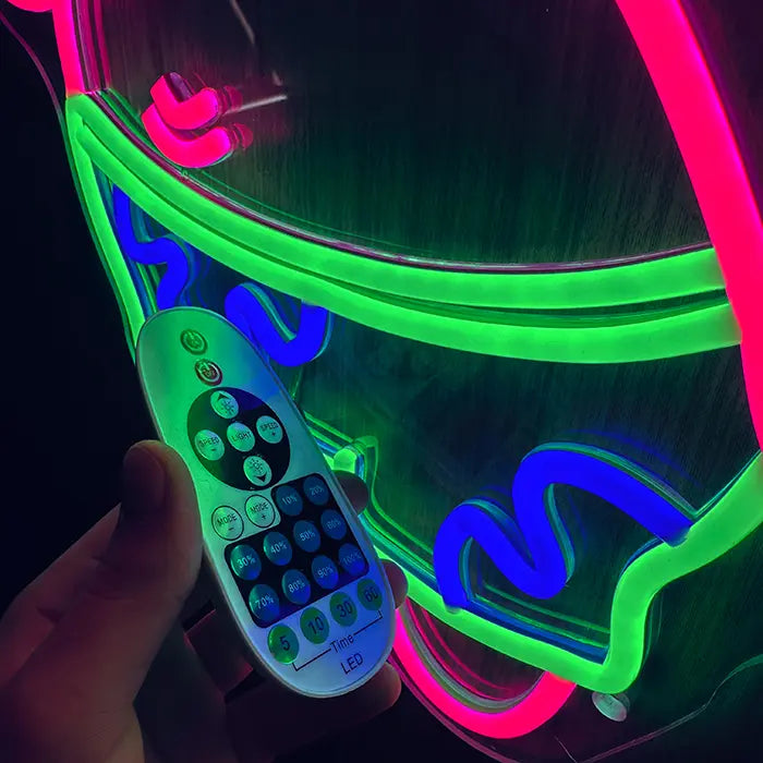 Patrick Middle Finger Neon LED Sign in close-up with the remote control in front of the green swim shorts