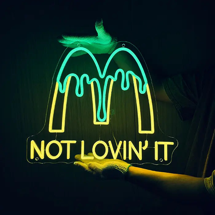 McDonald's Not Lovin' It Neon LED Sign being held against a dark wall with gloves