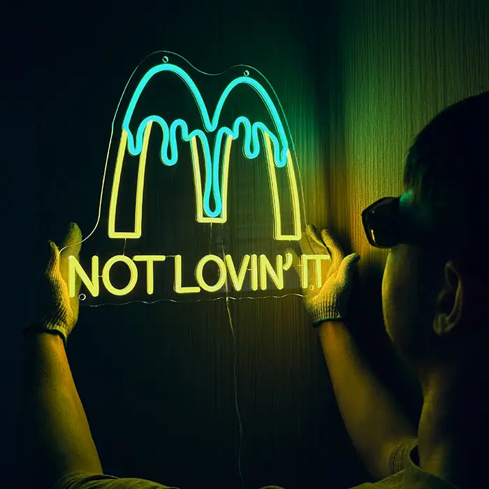 McDonald's Not Lovin' It Neon LED Sign being lined up on the wall, a person in gloves holds it in place