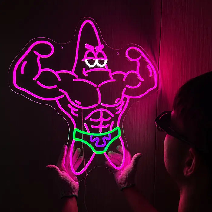 Patrick Bodybuilder Neon LED Sign being lined up on the wall, a person in gloves holds it in place