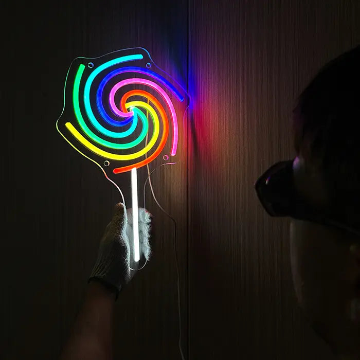 Lollipop Neon LED Sign on the wall, beside it a person in gloves checks the glow