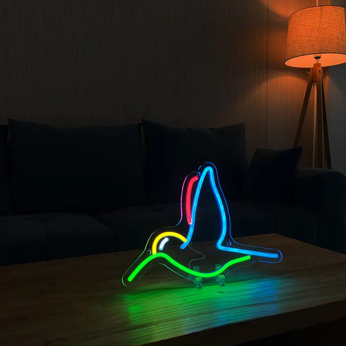 Hummingbird Bird Neon LED Sign on a wooden table in front of a sofa, next to it a floor lamp