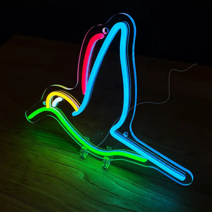Hummingbird Bird Neon LED Sign standing at an angle on a wooden table, the acrylic panel follows the outline