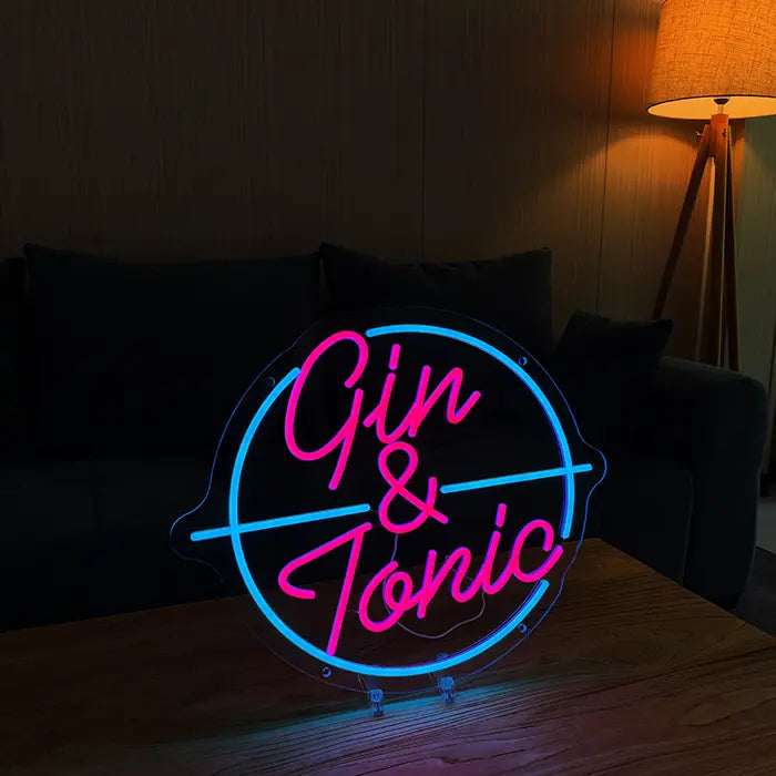 Gin & Tonic Neon LED Sign on stands on a wooden table, sofa and floor lamp behind