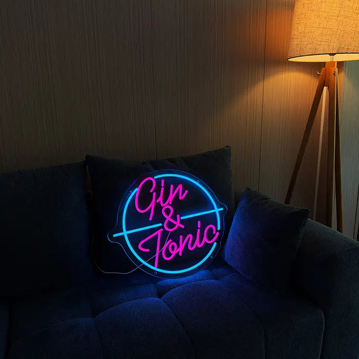Gin & Tonic Neon LED Sign set up on a dark sofa, next to it a floor lamp
