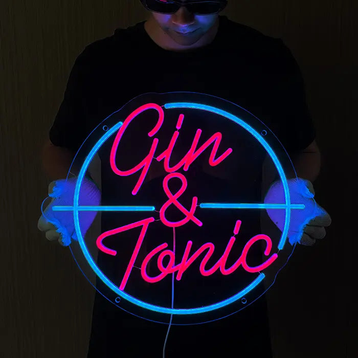 Gin & Tonic Neon LED Sign held in front of the body with gloves, pink lettering in a turquoise circle