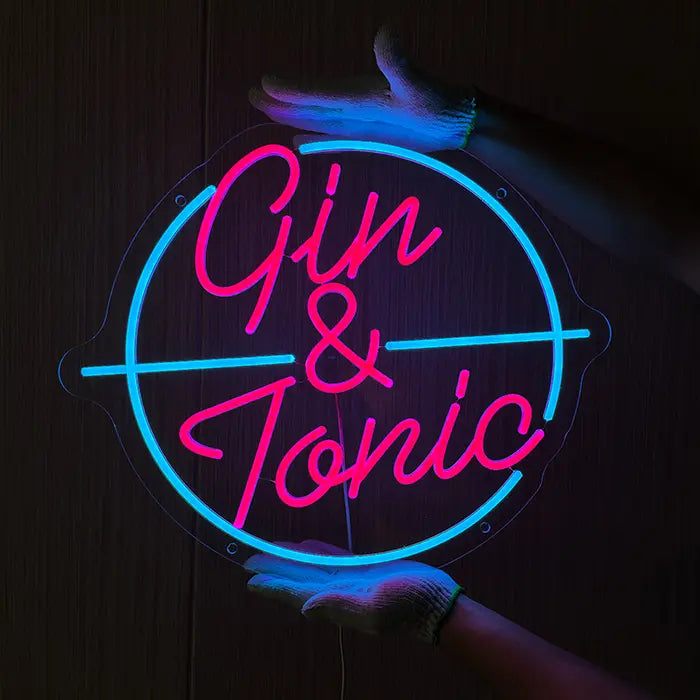 Gin & Tonic Neon LED Sign being held against a dark wooden wall with gloves