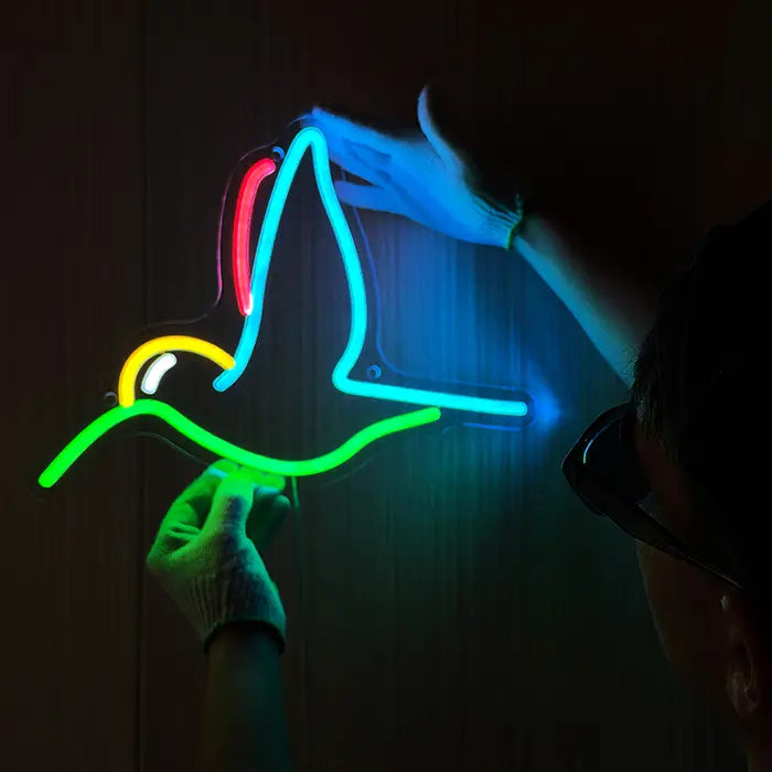 Hummingbird Bird Neon LED Sign being lined up on the wall, a person in gloves holds it in place