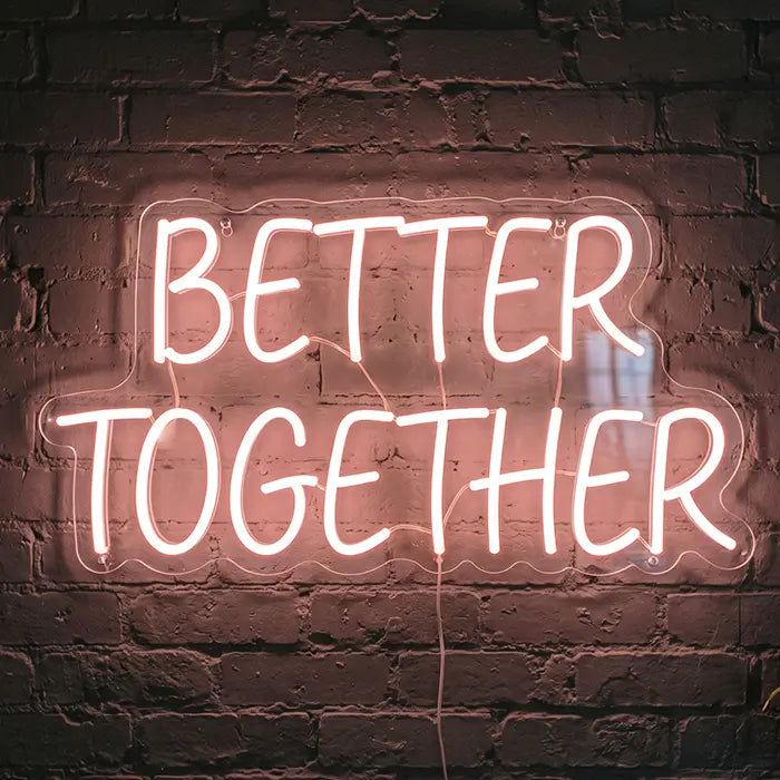 Better Together Neon LED Sign in warm white capitals on a brick wall