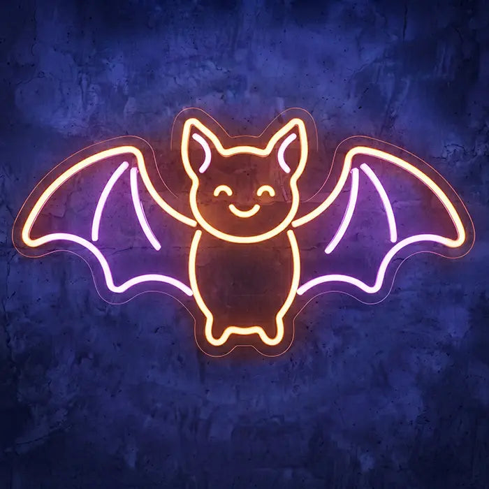 Fledermaus Neon LED Schild in Orange und Lila leuchtet an einer dunkelblauen Betonwand im Detail