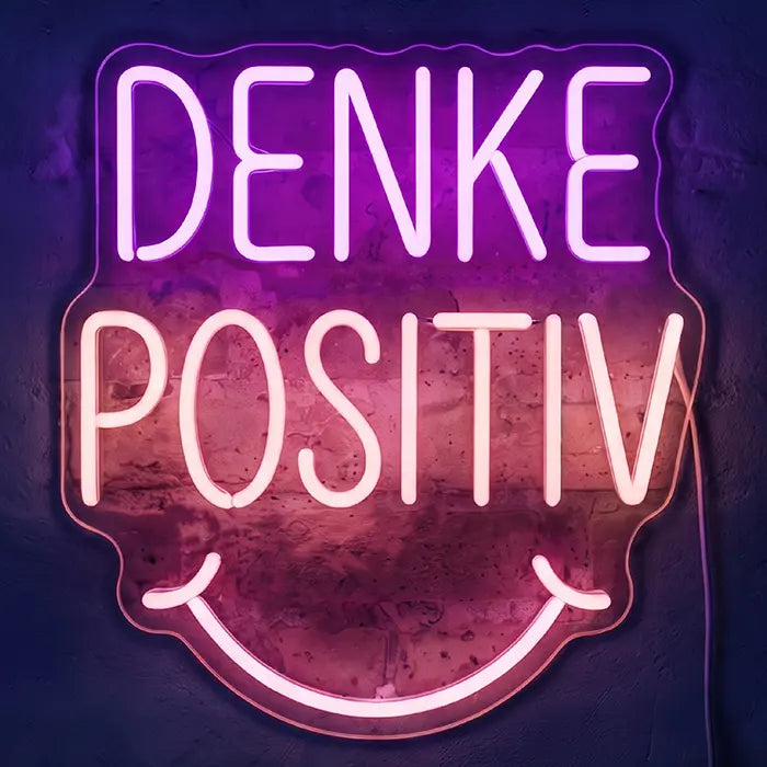 Denke Positiv Neon LED Schild in Lila und Weiß, Schriftzug mit Smiley-Mund vor dunkelvioletter Wand
