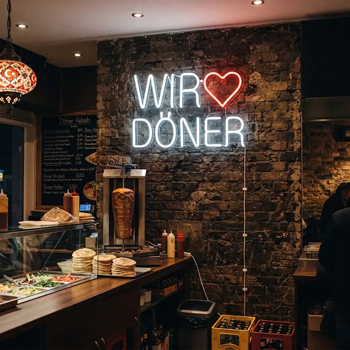 We Love Döner Neon LED Sign on a brick wall in a takeaway, the counter with a döner spit below