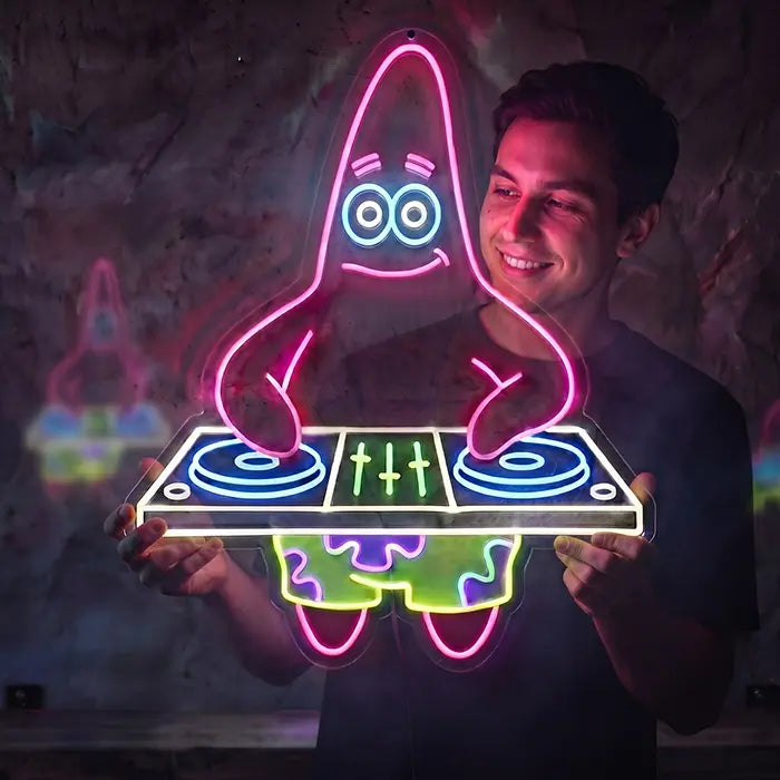 Patrick DJ Neon LED Schild wird von einem lachenden jungen Mann vor einer dunklen Wand hochgehalten