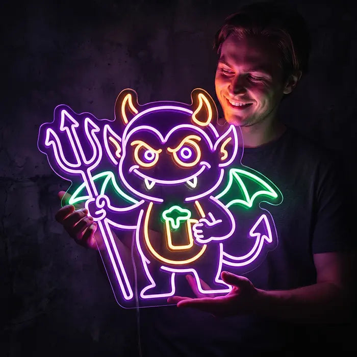 Teufel Neon LED Schild wird von einem lächelnden Mann vor einer dunklen Wand in den Händen gehalten