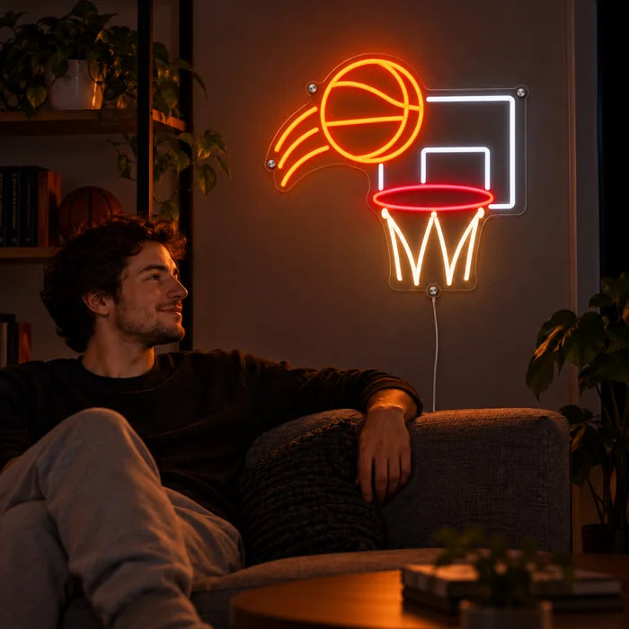 Koripalloheitto neon LED -kyltti olohuoneen seinällä, edessä henkilö rentoutuu sohvalla