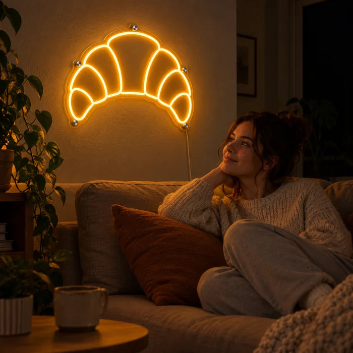 Butter Croissant Neon LED Sign on a living room wall, a person relaxing on the sofa in front of it