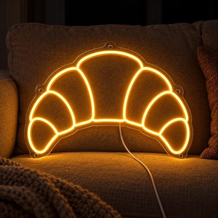 Butter Croissant Neon LED Sign on a cosy sofa between cushions and a throw