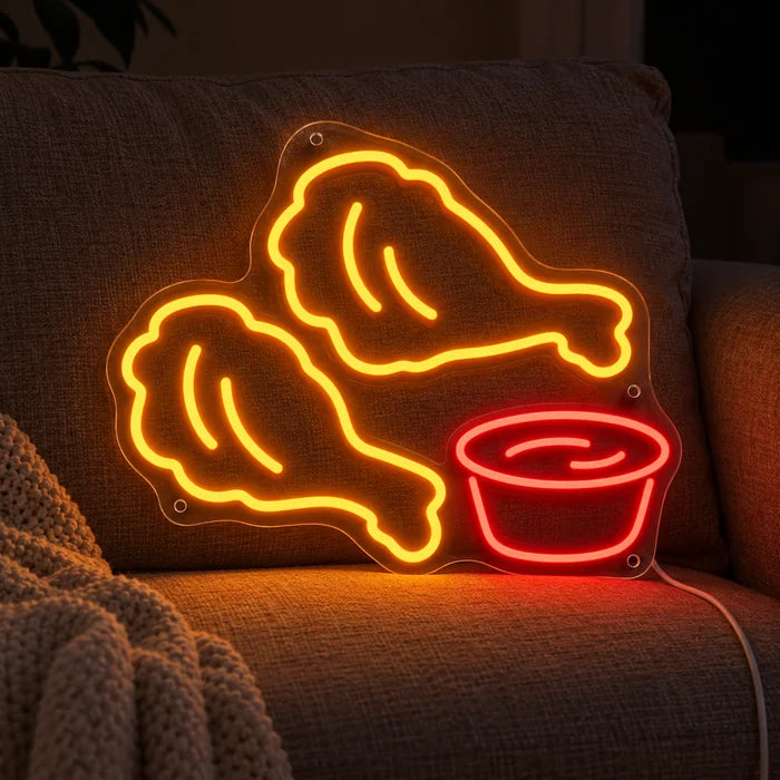 Cartel de neón LED Nuggets de pollo sobre un sofá acogedor entre cojines y manta