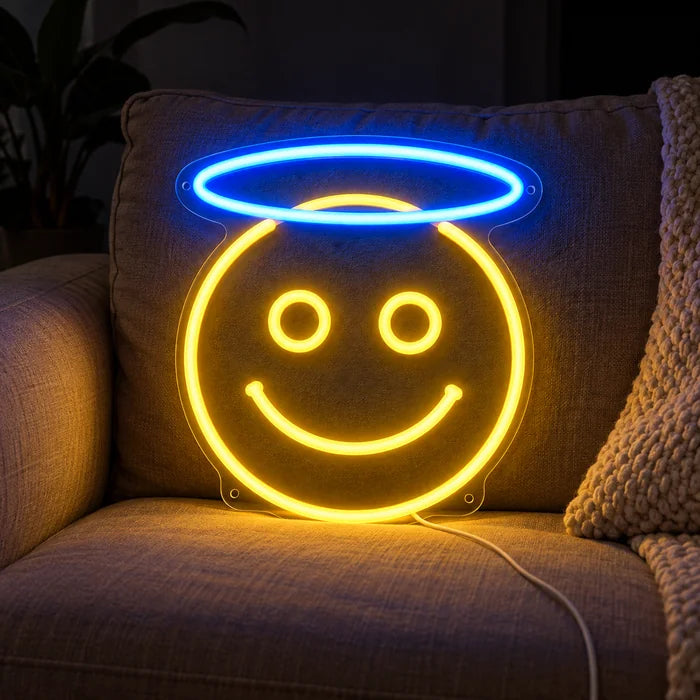 Angel Smiley Neon LED Sign on a cosy sofa between cushions and a throw