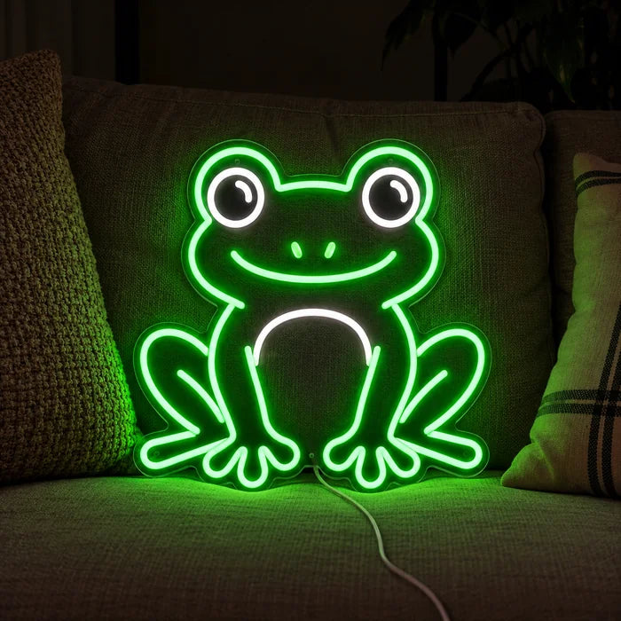 Frog Friend Neon LED Sign on a cosy sofa between cushions and a throw