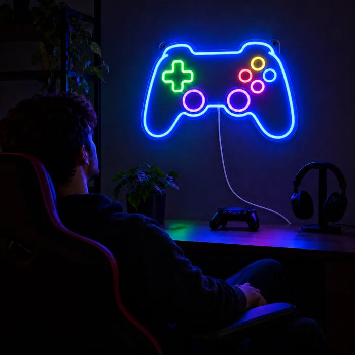 Insegna al neon LED Controller da gioco sopra la scrivania gaming, davanti un giocatore sulla sedia gaming