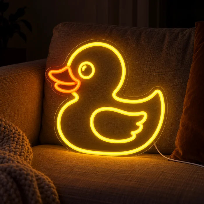 Yellow Duck Neon LED Sign on a cosy sofa between cushions and a throw